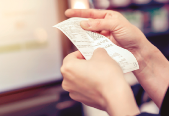 image: Photograph. Focus on a person's hands holding a receipt. end of image.